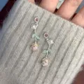 Close-up of elegant silver rose flower stud earrings with small pearls and green leaves. - Rose Pearl Stud Earrings (HE26277) / Silver-Pink