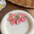 Close-up of artistic pink enamel flower stud earrings with elegant gold-tone edges. - Gold-Pink