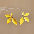 Macro detail of vibrant yellow enamel flower stud earrings with gold-toned edges - Gold-Yellow