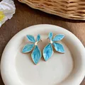 Detailed close-up of blue marble enamel flower stud earrings with gold-toned trim - Gold-Blue