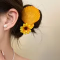 Close-up of a yellow shell hair clip with a fabric flower decoration on model's hair. - Shell Sunflower Style / Single Piece / Orange Yellow