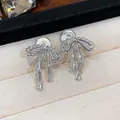 Macro view of silver lace bow-knot clip-on earrings displayed in a luxury jewelry box - One Pair / Silver