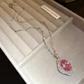 Elegante primer plano de un collar de lujo con colgante de circón rosa óvalo sobre terciopelo - Collar Plateado / Rosa