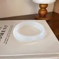 Gros plan détaillé d'un bracelet jonc en acrylique marbré blanc sur un livre chic - Blanc