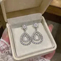 Detailed close-up view of sparkling zircon hollow teardrop earrings in a cream gift box - Silver