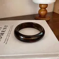 Vue détaillée d'un large bracelet en acrylique avec un riche motif écaille ambrée. - Marron