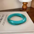 Gros plan d'un bracelet en acrylique marbré turquoise au design géométrique irrégulier. - Cyan
