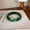 Détail d'un bracelet jonc en acrylique vert foncé avec marbrure blanche sur un livre blanc - Vert