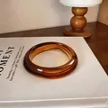 Gros plan d'un jonc rétro en acrylique ambré avec un motif marbré géométrique élégant - Marron