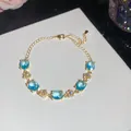 Close-up of 18k gold plated bracelet with oval blue zircons and flower details - Blue Oval Flower Style / Gold