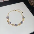 Macro view of elegant 18k gold plated bracelet featuring oval zircons and flowers - White Oval Flower Style / Gold