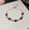 Detail view of silver-toned bracelet featuring vibrant oval red stones and delicate flowers - Red Oval Flower Style / Silver