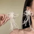 Detailed view of a bridal white feather flower jewelry set with pearls for an elegant look - Clip-On Earrings / White