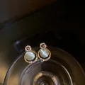 Macro view of exquisite cat's eye stone stud earrings featuring rhinestone G-letter design - Cat's Eye Stone Letter G Style (HE5225-1) / Gold