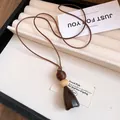 Vue détaillée d'un collier pendentif en résine marron avec des perles crème et cordon - Pendentif Principal Minimaliste (5) / Marron