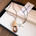 Détail d'un collier avec pendentif en résine et bois posé sur un plateau à bijoux - Style Rond Goutte (2) / Marron