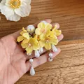 Detailed view of handmade yellow fabric flower earrings with elegant white pearl tassels. - Yellow