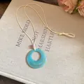 Detailed view of the blue resin donut pendant featuring a subtle marble texture on a beige cord - Round / Blue