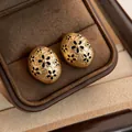 Close-up of French vintage golden oval earrings with black flower patterns in a box - Gold Black