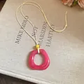 Close-up of a pink resin ring pendant on a beige cord necklace, vintage style detail - Square / Pink