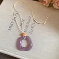 Detailed macro view of a vintage purple resin ring pendant necklace with an elegant cord. - Square / Purple