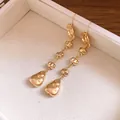 Gros plan de boucles d'oreilles pendantes dorées à texture froissée irrégulière - Gland Plissé Irrégulier (HE33531) / Or