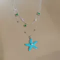 Detailed view of the blue enamel starfish pendant with green zircon charms on silver chain - Silver-Blue