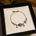 Elegant silver chain bracelet featuring green zircon with shell and starfish charms - Silver-Green