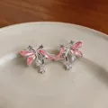 Gros plan de boucles d'oreilles fleur en émail rose avec zircone sur une assiette. - Rose