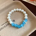 Detailed view of an elegant beaded bracelet with white pearls and blue cat-eye stones. - Bracelet / White-Blue