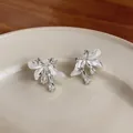 Vue détaillée de boucles d'oreilles fleurs en argent avec émail blanc et zircons. - Blanc