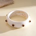 Detailed view of a vintage marbled resin bangle featuring amber-toned rivet studs - White
