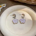 Macro view of sweet purple resin flower pendant earrings with delicate pearl centers - Purple