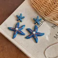 Dettaglio di orecchini a stella marina blu con strass rossi e perla centrale decorata - Stile a Goccia Stella Marina / Blu