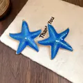 Close-up detail of summer vacation style blue oil-dripped starfish earrings with gold trim. - Starfish Style (Silver Post) / Blue
