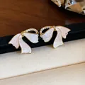 Nahaufnahme eleganter 18k vergoldeter Schleifenohrringe mit Zirkonia-Inlay und Marmortextur - Schleife (HE31281) / Silberstift-Gold-Weiß