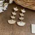 Close-up of multi-tier fan-shaped earrings with 18k gold plating and sparkling stones. - Silver Post Style (Real Gold Plated) / White