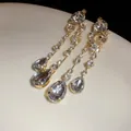 Nahaufnahme eleganter goldener Tropfenohrringe mit glitzernden Strasssteinen - Stil mit Silber-Ohrstecker / Gold-Weiß
