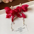 Close-up of red fabric flower earrings with elegant pearl and crystal tassel details - Silver Needle Gold Style / Red