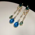 Detailansicht eleganter goldener Ohrhänger mit blau-grünen Wassertropfen-Strasssteinen - Stil mit Silber-Ohrstecker / Blau-Grün