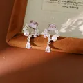 Gros plan de boucles d'oreilles en argent avec perles, zircons et cristaux violets - Style de tige d'oreille en argent / Rose