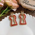 Close-up detail of vintage red keyhole earrings with gold trim and rhinestones. - Red Keyhole Geometric Style