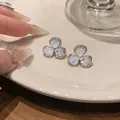 Elegant clover flower stud earrings with shimmering zircon stones and iridescent center - Silver