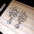 Macro detail of silver-tone floral clip-on earrings with clear crystal teardrops - Ear Clips (Silver Color) / Silver