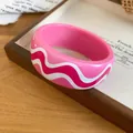 Close-up of pink resin bangle with stylish wavy print for a resort vacation look. - Pink And Magenta