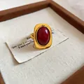 Nahaufnahme eines Vintage-Goldrings mit rotem Harzstein auf Stoff - Rot Oval / Gold