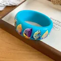 Detail shot of a vibrant blue resin bangle featuring colorful tropical fish prints - Blue Multicolor