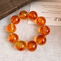 Nahaufnahme eines bernsteinfarbenen Acryl-Armbands mit goldenen Zwischenstücken. - Armband / Braun