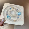 Makrodetail eines eleganten schillernden Glasperlenarmbands mit blauen Herzanhängern. - Regenbogen-Herzform (2#) / Weiß-Blau