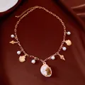 Detailed view of a gold chain necklace with pearls and a large natural shell pendant. - Gold